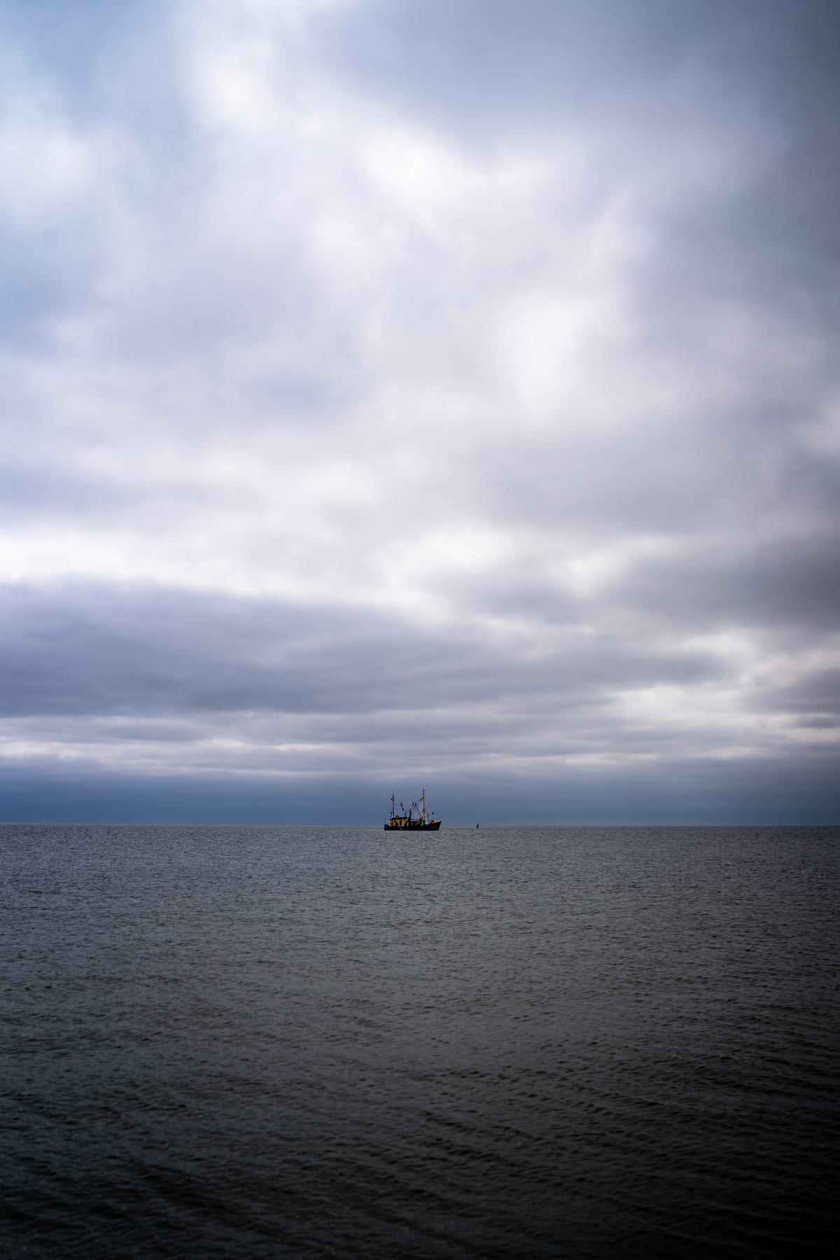 A small ship on the North Sea beneath a thick layer of clouds.